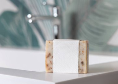 Yeşil tropikal banyodaki lavabonun yanındaki boş muslukta bej sabun barı, fotokopi alanı ile ambalajlama. Günlük hijyen için markasız doğal bitki ürünü.