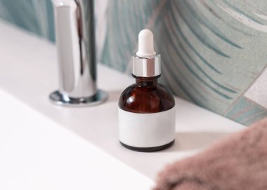 Kahverengi havluların yanında pipet ve yeşil tropikal banyodaki havuzun üstünde musluk olan kahverengi cam damlalar. Etiket modeli. Kopya alanı olan doğal markasız kozmetik ürünler. Spa konsepti