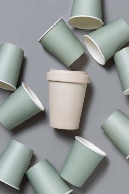 Tek kullanımlık yeşil kağıt bardaklar ve gri üst manzaralı yeniden kullanılabilir bambu kahve fincanı, fotokopi alanı ile taklit edilmiş. Boş kahve fincanları düz yerde. Plastik ve sürdürülebilir yaşam tarzı kavramı yok 