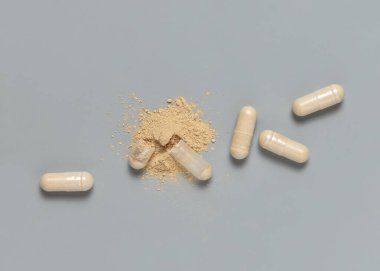 Tıbbi kapsüller gri üst görünümde bej tozu göstermek için bir tanesini açtı. Koruyucu tıp ve sağlık, alternatif beslenme takviyeleri ve vitaminler almak 