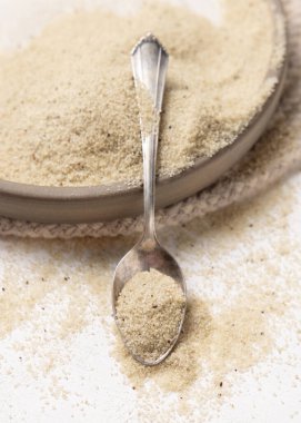 Çiğ fonio tohumları bir tabakta, beyaz masada metal bir kaşık, yakın plan, kopyalama alanı. Afrika 'nın antik sahte tahtaları. Organik süper yiyecekler. Sağlıklı gıda konsepti. Glütensiz alternatif tohumlar