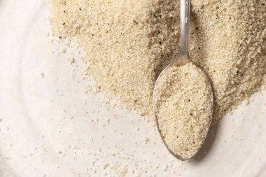 Çiğ fonio tohumları beyaz masa manzarasında metal bir kaşıkta, kopyalama alanı. Afrika 'nın antik sahte tahtaları. Organik süper yiyecekler. Sağlıklı gıda konsepti. Glütensiz alternatif tohumlar