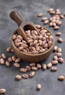 Kurutulmuş fasulye dolu ahşap bir kase ve yakın plan gri masa. Sağlıklı vejetaryen yemekleri, protein kaynakları. Geleneksel Latin Amerikalı kuzen malzemesi