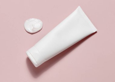 Beyaz boş sıkma kozmetik tüpü krema lekesi yanında açık pembe üst görünümde, makette, kopyalama alanında. Cilt kremi ya da güzellik ve spa için vücut losyonu, asgari estetik. Günlük kişisel bakım