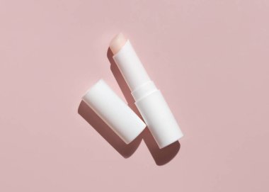 Açık beyaz dudak kremi çubuğu açık, açık pembe kapaklı, koyu gölge görüşlü, model, negatif alan. Erkeklerin günlük kişisel bakımı için Lipcare güzellik ürünü, minimal stil estetik 