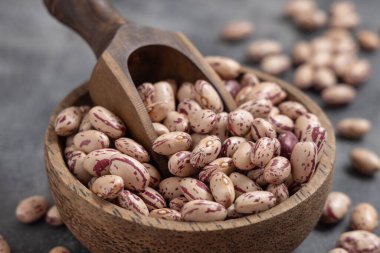 Kurutulmuş fasulye dolu ahşap bir kase ve yakın plan gri masa. Sağlıklı vejetaryen yemekleri, protein kaynakları. Geleneksel Latin Amerikalı kuzen malzemesi