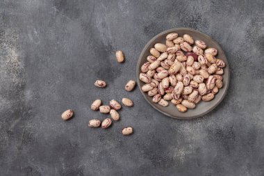 Gri masa manzaralı kuru fasulye dolu seramik tabak, kopyalama alanı. Sağlıklı vejetaryen yemekleri, protein kaynakları. Geleneksel Latin Amerikalı kuzen malzemesi