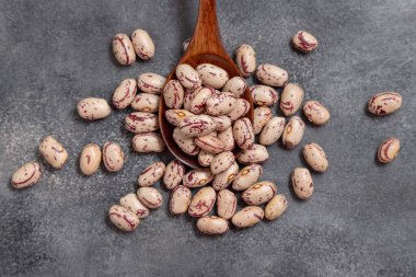 Gri masa manzaralı kuru fasulye dolu ahşap kaşık. Sağlıklı vejetaryen yemekleri, protein kaynakları. Geleneksel Latin Amerikalı kuzen malzemesi