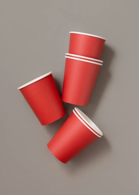 Koyu gri arka plan görünümlü, tek kullanımlık kırmızı kağıt bardaklar, reklam alanı olan maketler. Boş karton kahve fincanları düz yerde. Plastik ve sürdürülebilir yaşam tarzı kavramı yok 