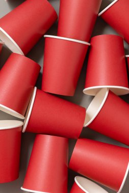 Koyu gri arka plan görünümlü, tek kullanımlık kırmızı kağıt bardaklar, reklam alanı olan maketler. Boş karton kahve fincanları düz yerde. Plastik ve sürdürülebilir yaşam tarzı kavramı yok 