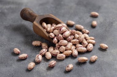 Gri masa üzerinde kurutulmuş fasulye dolu ahşap kepçe. Sağlıklı vejetaryen yemekleri, protein kaynakları. Geleneksel Latin Amerikalı kuzen malzemesi