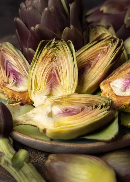 Koyu kırsal masa üzerinde kesilmiş mor, çiğ romanesko enginarlarla dolu bir tabak. Çiftçi pazarından alınmış taze sebzeler. Temizlik yapıyor ve yemek yapmaya hazırlanıyor. İtalyan kuzeni.