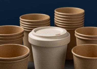 Tek kullanımlık yeni bej kraft kağıt bardaklar ve gri ve mavi yakın plan üzerinde yeniden kullanılabilir bambu kahve fincanı, kopyalama alanı olan maketler. Boş kahve fincanları. Plastik ve sürdürülebilir yaşam tarzı kavramı yok 