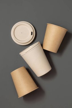 Tek kullanımlık yeni bej kraft kağıt bardaklar ve gri üst manzaralı yeniden kullanılabilir bambu kahve bardağı, kopyalama alanı olan maketler. Boş kahve fincanları. Plastik ve sürdürülebilir yaşam tarzı kavramı yok 