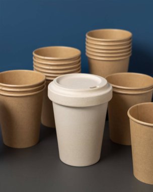 Tek kullanımlık yeni bej kraft kağıt bardaklar ve gri ve mavi yakın plan üzerinde yeniden kullanılabilir bambu kahve fincanı, kopyalama alanı olan maketler. Boş kahve fincanları. Plastik ve sürdürülebilir yaşam tarzı kavramı yok 