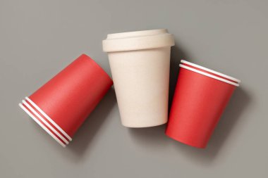 Tek kullanımlık yeni kırmızı bardaklar ve gri üst manzaralı bej yeniden kullanılabilir bambu kahve fincanı, fotokopi alanı ile modelleme. Boş kahve fincanları. Plastik ve sürdürülebilir yaşam tarzı kavramı yok 