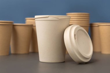 Tek kullanımlık yeni bej kraft kağıt bardaklar ve gri ve mavi yakın çekim üzerine yeniden kullanılabilir bambu kahve bardağı, maket, kopyalama alanı. Boş kahve fincanları. Plastik ve sürdürülebilir yaşam tarzı kavramı yok 