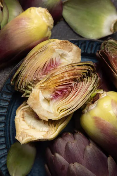 Koyu kırsal masa manzaralı, kesilmiş mor, çiğ Roma enginarlarıyla dolu bir tabak. Çiftçi pazarından alınmış taze sebzeler pişirmeye hazır. İtalyan kuzeni.