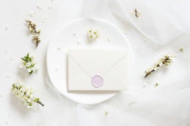 Kapalı zarf tülün yanında ve yaban erikleri beyaz çiçekler üst manzara, maket. Bahar partisi tasarımı için Pastel yatay kart, anneler günü veya romantik düğün kırtasiyesi