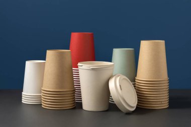 Tek kullanımlık yeni renkli kağıt bardaklar ve gri ve mavi yakın plan üzerinde yeniden kullanılabilir bambu kahve fincanı, kopyalama alanı olan maketler. Boş kahve fincanları. Plastik ve sürdürülebilir yaşam tarzı kavramı yok 