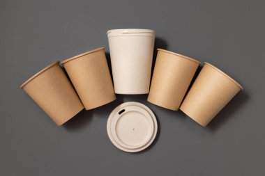 Tek kullanımlık yeni bej kraft kağıt bardaklar ve gri üst manzaralı yeniden kullanılabilir bambu kahve bardağı, kopyalama alanı olan maketler. Boş kahve fincanları. Plastik ve sürdürülebilir yaşam tarzı kavramı yok 