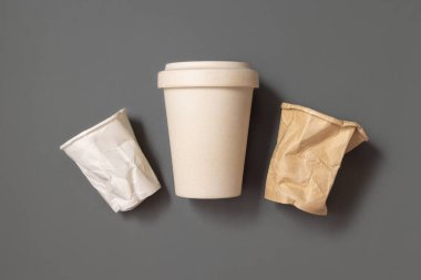Kullanılmış ve buruşmuş kağıt bardaklar ve gri üst görüşlü yeniden kullanılabilir bambu kahve fincanı, kopyalama alanı, maket. Tüketim konsepti. Plastik ve sürdürülebilir yaşam tarzı kavramı yok 