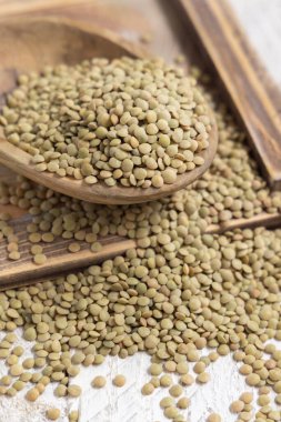 Tahta kase, beyaz masada kurutulmuş çiğ yeşil mercimek. Sağlıklı çiğ vejetaryen yiyecekler, baklagiller bitkisel protein kaynakları. Geleneksel Akdeniz malzemesi