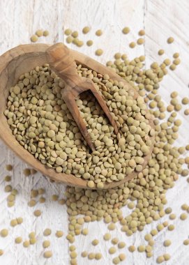 Beyaz masa manzaralı küçük bir kase dolusu kurutulmuş yeşil mercimek. Sağlıklı vejetaryen yiyecekler, bitkisel protein kaynakları. Geleneksel Akdeniz çiğ malzemesi