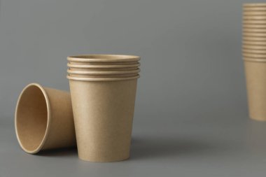 Koyu gri arka planda tek kullanımlık kağıt bardaklar. Reklam alanı olan bir model. Boş karton kahve fincanları. Plastik ve sürdürülebilir yaşam tarzı kavramı yok 