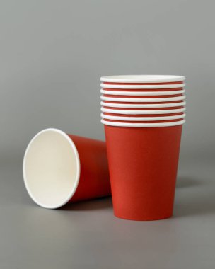 Koyu gri arka planda tek kullanımlık kırmızı bardaklar. Reklam alanı olan bir model. Boş karton kahve fincanları düz yerde. Plastik ve sürdürülebilir Noel kavramı yok 