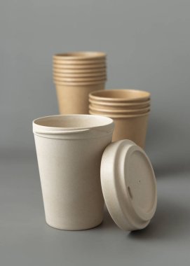 Tek kullanımlık yeni bej kraft kağıt bardaklar ve yeniden kullanılabilir gri kapaklı bambu kahve fincanı, kopyalama alanı olan maketler. Boş raptiye kahve fincanları. Plastik ve sürdürülebilir yaşam tarzı yok 