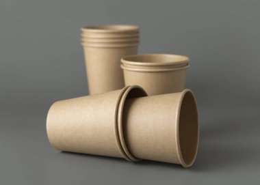 Koyu gri arka planda tek kullanımlık kağıt bardaklar. Reklam alanı olan bir model. Boş karton kahve fincanları. Plastik ve sürdürülebilir yaşam tarzı kavramı yok 