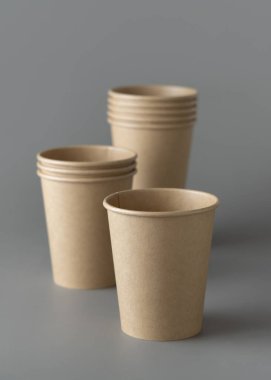 Koyu gri arka planda tek kullanımlık kağıt bardaklar. Reklam alanı olan bir model. Boş karton kahve fincanları. Plastik ve sürdürülebilir yaşam tarzı kavramı yok 