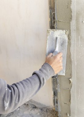 Zanaatkar, duvar veya kapı aralığını kaplamak için şamandıra ve çimento kullanır. İnşaat veya yenileme çalışmaları sırasında gri iş elbiseli genç erkekler