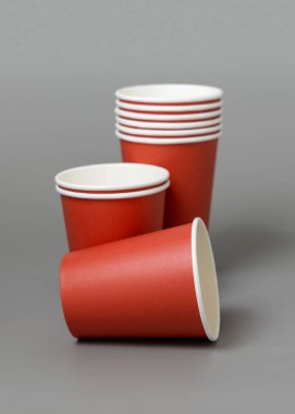 Koyu gri arka planda tek kullanımlık kırmızı bardaklar. Reklam alanı olan bir model. Boş karton kahve fincanları düz yerde. Plastik ve sürdürülebilir Noel kavramı yok 