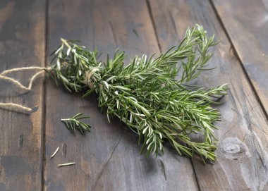 Koyu eskimiş ahşap masa üzerinde bir demet taze biberiye filizi. Et ve balık için otlar. Akdeniz mutfağı konsepti