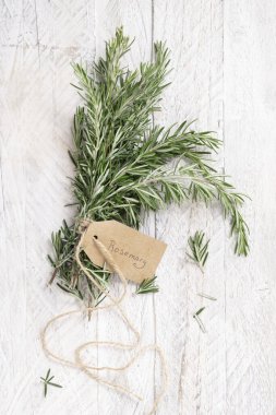 Beyaz yıpranmış ahşap masa manzaralı Kraft kağıt metin etiketli taze biberiye filizleri. Aromatik olsun.