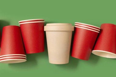 Tek kullanımlık kırmızı bardaklar ve yeşil üst manzaralı bej renkli bambu kahve fincanı. Kopya alanı olan Noel modeli. Boş kahve fincanları. Plastik ve sürdürülebilir yaşam tarzı kavramı yok 