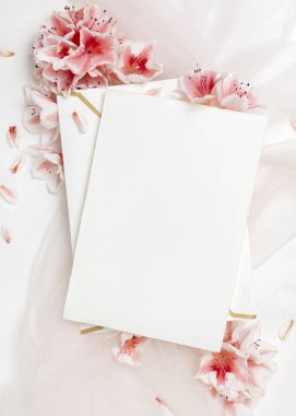 Pembe açelya çiçeklerinin yakınındaki zarfın üzerindeki boş kağıt kart üst görünüm, kopyalama alanı, maket. İlkbahar romantik düğün kırtasiyesi ya da parti tasarımı için dikey kart, Anneler Günü ya da doğum günü havası