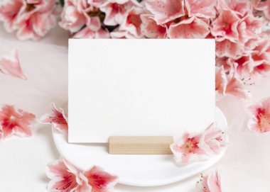 Pembe açelya çiçeklerinin yanındaki boş kağıt kart yakın plan, kopyalama alanı, maket. Bahar romantik düğün kırtasiyesi veya parti tasarımı için yatay kart, Anneler Günü veya doğum günü havası