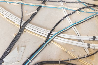 Plastik elektrik boruları bitmemiş bir odanın zeminine konur. Yeni bina, ev ya da ofis içinde elektrik sistemi inşaatı.  