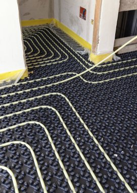 Yeni bir binada zemin ısıtma tesisatı, plastik borular ve boru hatları siyah yalıtım kağıdına monte ediliyor. Yeni bir evde, iç mimaride yer altı ısıtma sistemi.