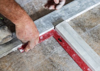 Marangoz fayanstan önce evin zeminindeki açıları ölçüyor. Eller yakın. Ev iç dekorasyonu. Yeni bir binanın inşaatı 