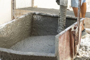 İnşaat sırasında mikserden el arabasına taze hazır beton dökülüyor. Endüstri için beton. Hammadde, endüstriyel süreç ve inşaat sahneleri temaları için mükemmel