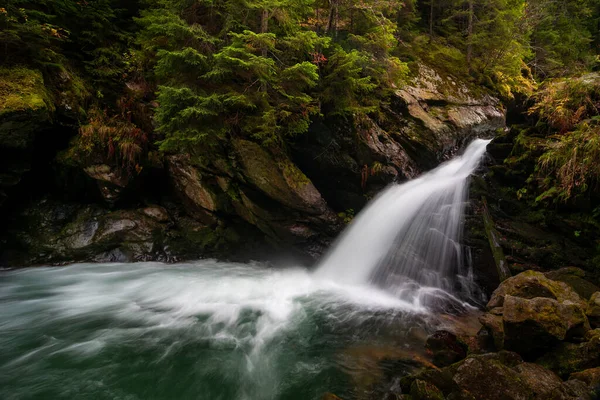 stock image Waterfall flowing through rocks in a deep forest, autumn landscape