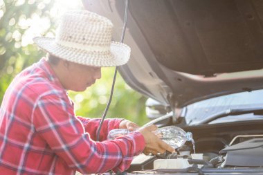 Close up man refill water to tank of car radiator and checking up the engine before start the trip. Car maintenance or check up concept