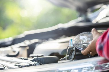 Close up man refill water to tank of car windshield wiper and checking up the engine before start the trip. Car maintenance or check up concept