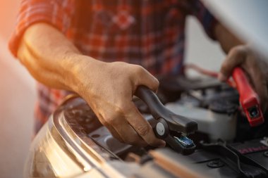 Car broken on the road. Man holding red and black battery cable for charging the car. Car Repair and maintenance concept