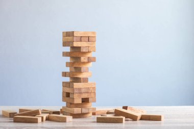 Risky of Stack tower wooden block game on the table with grey space wall background