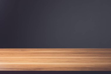 Ahşap masanın üst katı boş. Koyu gri duvar zemininde kahverengi ahşap masa. Mockup veya ürün reklamcılığı için